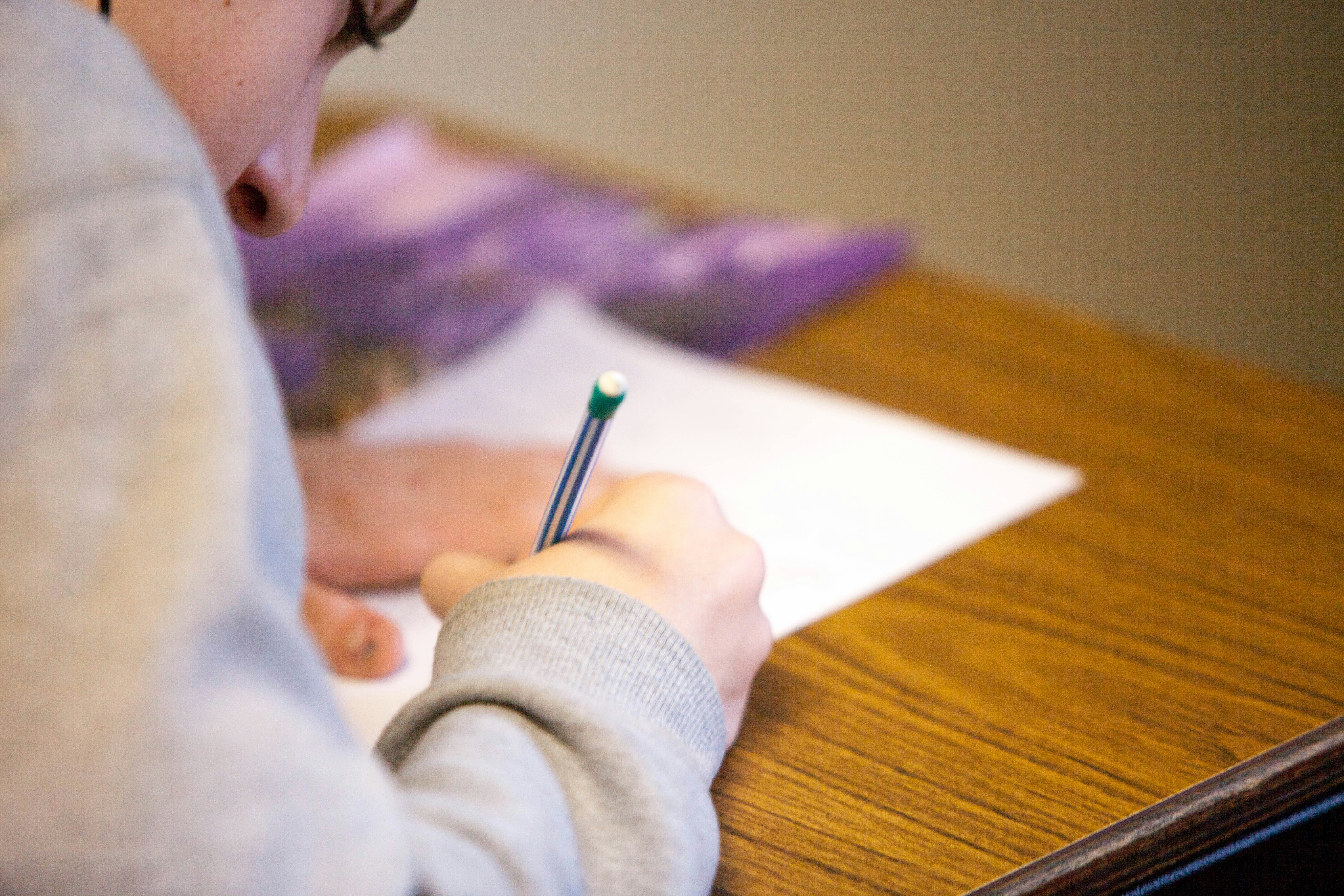 A person writing an exam at a table.